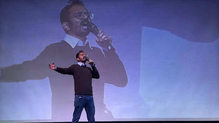 Dr. Bhaskar Das singing on stage at a college event
